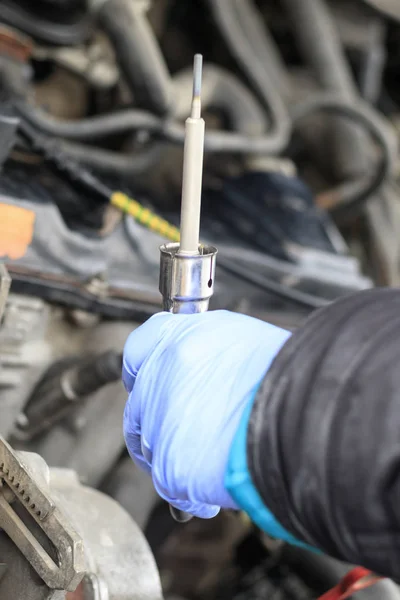 Master in blue gloves check the candle. engine compartment in the car. close-up. — Stock Photo, Image