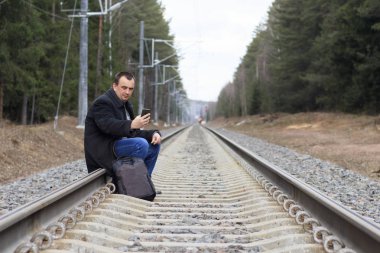 Tren. Ceket bir adam, bir karanlık. telefon elinde Ray üzerinde oturdu. sırt çantası. Orada tonlama.