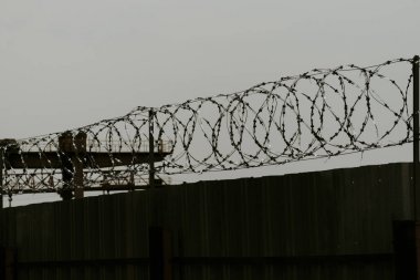 Tel üstündeki metal çit. üzerinde dikenler var. akşam geç saatlerde vuruldu. Her şey kasvetli görünüyor