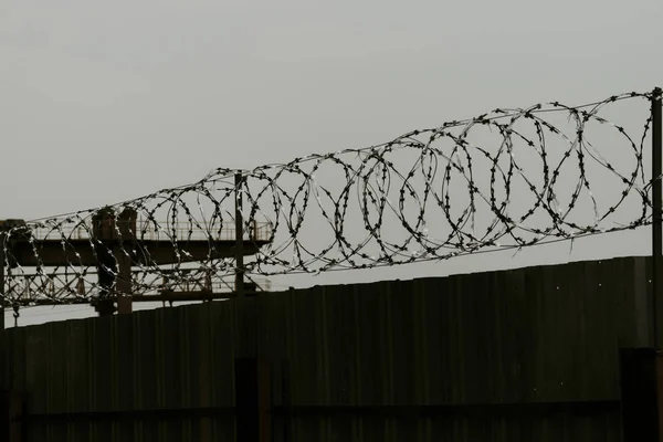 Metalen hek aan de bovenkant van de draad. Er zijn doornen op. geschoten laat in de avond. Alles ziet er somber — Stockfoto