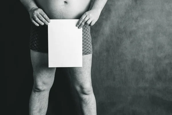 Un hombre en pantalones cortos en el fondo de la junta escolar, en sus manos tiene una hoja de papel en blanco . —  Fotos de Stock