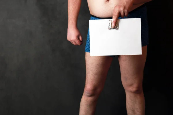 Un hombre en pantalones cortos en el fondo de la junta escolar, en sus manos tiene una hoja de papel en blanco . — Foto de Stock