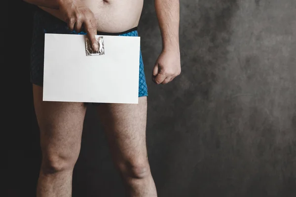 Un hombre en pantalones cortos en el fondo de la junta escolar, en sus manos tiene una hoja de papel en blanco . —  Fotos de Stock