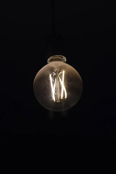 Incandescent lamp, illuminated in total darkness. the light is dim. there is toning. — Stock Photo, Image