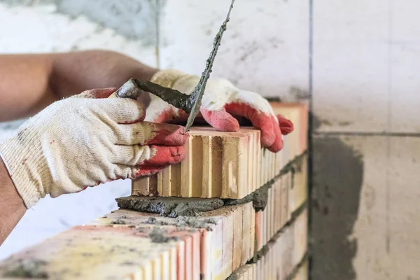 Meester met een gereedschap, stapelt een rode baksteen. Er is verlichting en toning. ondiepe snedediepte. — Stockfoto