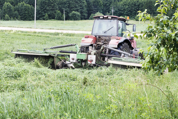 Tractor mows the grass. harvesting hay for the winter