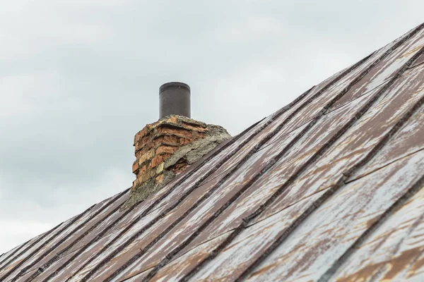 Металлическая крыша, краска почти исчезла. на дымоходе. труба и керпич . — стоковое фото