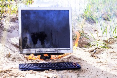 plaj kumu. parlak güneş. monitör dumanla yanar. klavyesi var.