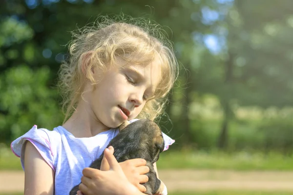 Flickan håller en mycket liten valp. Dagsljus. Närbild. — Stockfoto