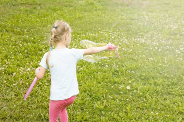 küçük kız, sarışın, çayırda oynarken ve bir kabarcık darbeler.