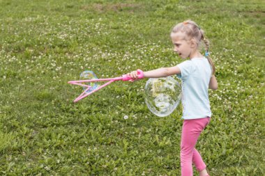 küçük kız, sarışın, çayırda oynarken ve bir kabarcık darbeler.
