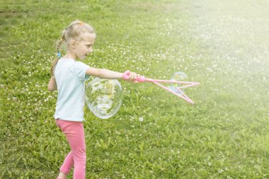 küçük kız, sarışın, çayırda oynarken ve bir kabarcık darbeler.
