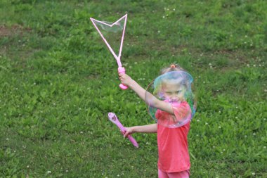 küçük kız, sarışın, çayırda oynarken ve bir kabarcık darbeler.