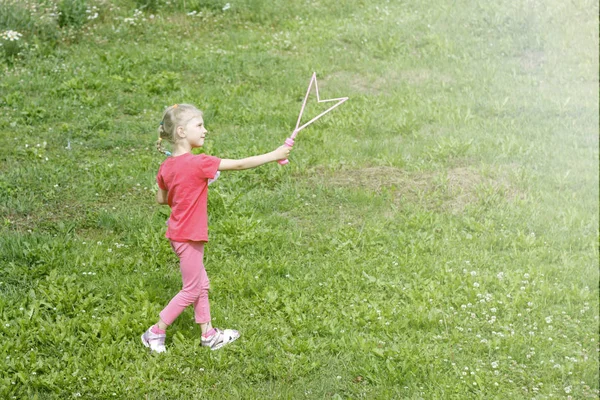 Menina, loira, brincando no prado, e sopra uma bolha . — Fotografia de Stock
