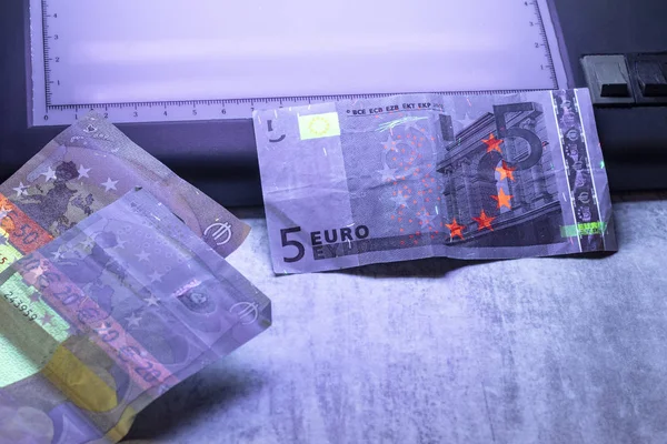 5 euro authenticatie. ultraviolet licht schijnt op hen. — Stockfoto