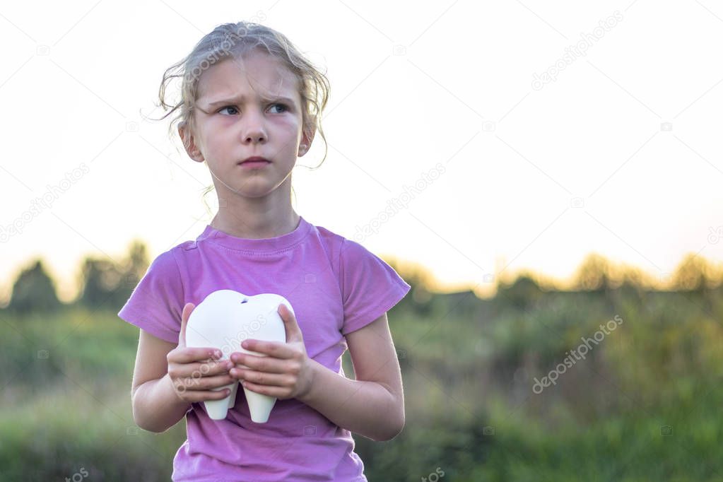 little girl affliction. holds a large plaster tooth. Shallow depth of field