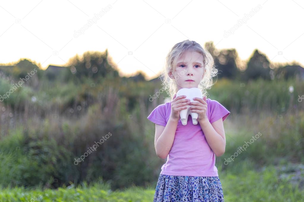 little girl affliction. holds a large plaster tooth. Shallow depth of field