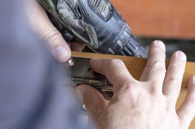 ana kapı menteşesini ayarlar. bir aletle delik açar