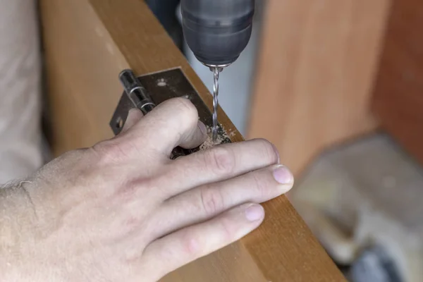 The master sets the door hinge. drills a hole with a tool — Stock Photo, Image