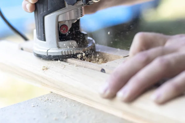 Installing a door, Install a door lock, use a milling saw, a carpenter close-up holds a green electric drill — Stock Photo, Image