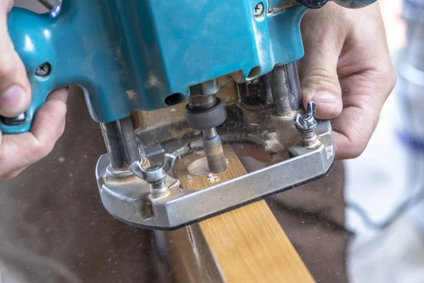 Installing a door, Install a door lock, use a milling saw, a carpenter close-up holds a green electric drill — Stock Photo, Image