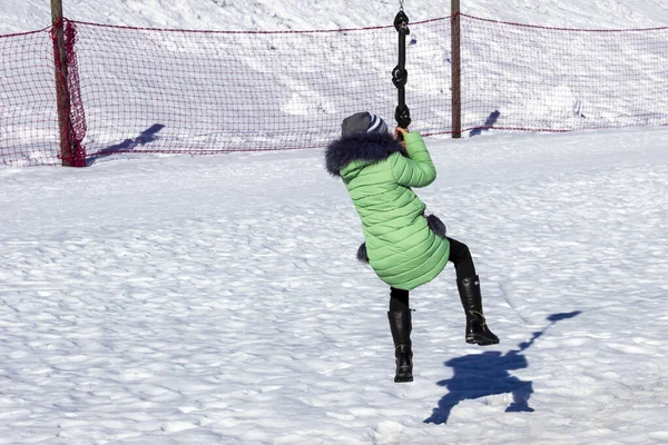 Día soleado en invierno. nieve por todas partes. chica en una chaqueta blanca cae de un bungee — Foto de Stock