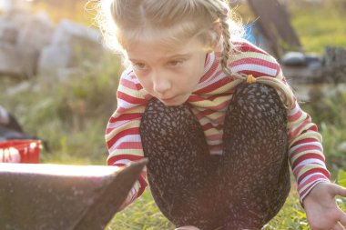 Gün batımı. Sarışın kız fırçayla metal bir merdiven boyuyor. Rengi kırmızı. Burada bir kepenk var. Yumuşak odaklanma. renklendirme.