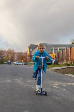 Ön plan. Beyaz saçlı, mavi ceketli, scooter süren bir kız. Ve bize elini uzat..