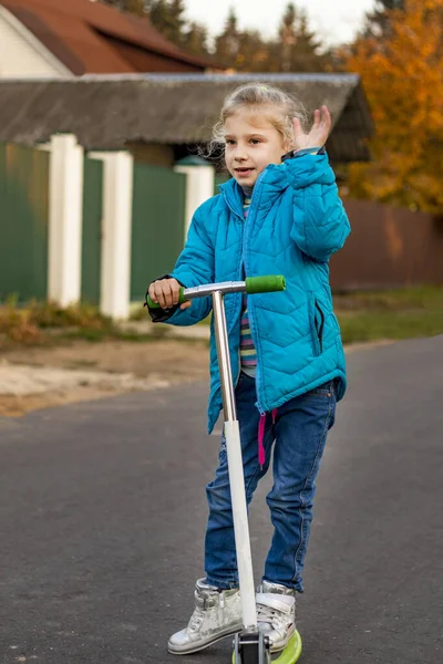 Primeiro plano. uma menina com cabelo branco e em uma jaqueta azul montando uma scooter. e nos moshet mão . — Fotografia de Stock