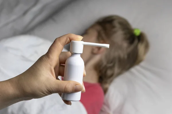 A girl with white hair lies in bed she is out of focus. mom using an inhaler makes an injection in the patient's throat, she is in focus. — Stock Photo, Image