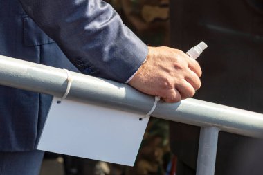 Gün ışığı. Erkek elinde metal bir korkuluk var. Küçük bir şişede antiseptik var..