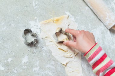 Ev mutfağı. Masanın üzerinde pişirmek için bir hamur var. Bir çocuk içine bir form sıkıştırıyor..