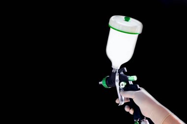Lastik eldivendeki bir el mekanik bir atomizer tutar. Siyah arkaplan.