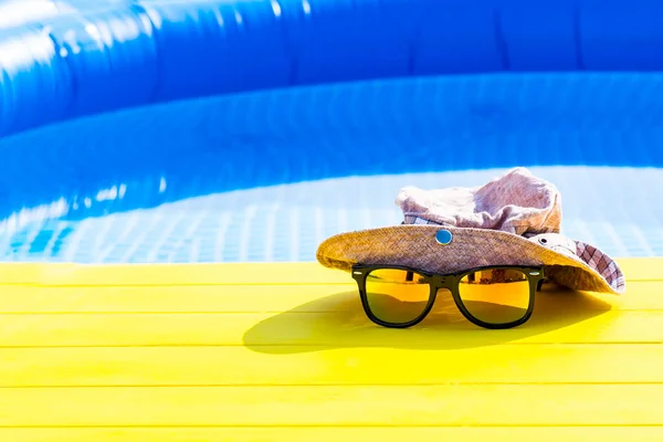daylight. yellow background in retro style. He is wearing a hat and sunglasses. No focus on the pool. Copy space