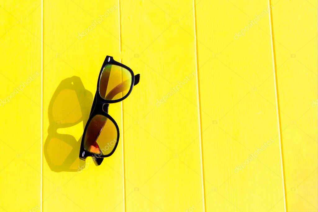 Daylight. bright sun. Clear shadows. Wooden background in yellow. He is wearing sunglasses.