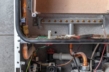 Usta, duvara ağırlık veren bir gaz kazanı kuruyor. Ön torpido gözü açık. Uygunsuz bakım nedeniyle, içinde bir sürü harici çöp toplandı. Bu hasar ve yangına neden olabilir.