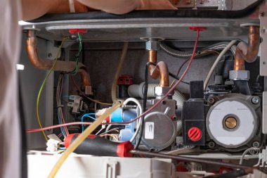 Usta, duvara ağırlık veren bir gaz kazanı kuruyor. Ön torpido gözü açık. Bir fırça ve endüstriyel elektrik süpürgesi kullanarak, pislikten ve pislikten temizlenerek.