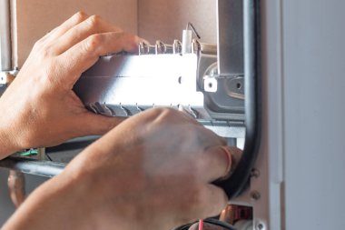 Usta, duvara ağırlık veren bir gaz kazanı kuruyor. Ön torpido gözü açık. Gaz tedariği için gaz başlıklarının kaldırılması ve kurulumu.