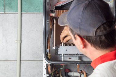 Usta, duvara ağırlık veren bir gaz kazanı kuruyor. Ön torpido gözü açık. Gaz tedariği için gaz başlıklarının kaldırılması ve kurulumu.