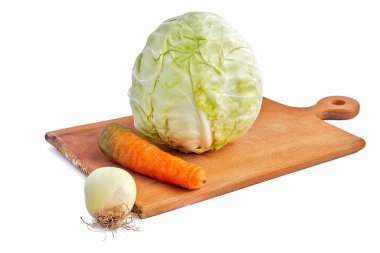 Beyaz arka plan. İzolasyon yok. Kesme tahtasında taze lahana, havuç ve soğan. Yakın plan.