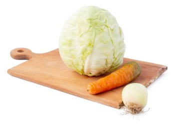 Beyaz arka plan. İzolasyon yok. Kesme tahtasında taze lahana, havuç ve soğan. Yakın plan.