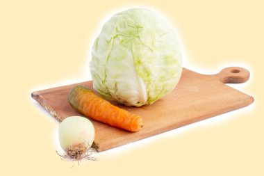 Beyaz arka plan. İzolasyon yok. Kesme tahtasında taze lahana, havuç ve soğan. Yakın plan.