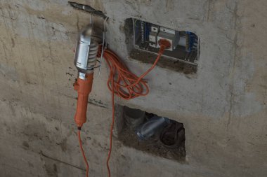 Garaj. Beton duvarlar boyanacak. Bir turuncu taşıyıcı arabanın teftişi ve onarımları için onu asıyor.