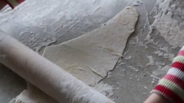 Mutfak. Masa. Üzerinde, çocuk ev yapımı hamuru merdaneyle yuvarlıyor. Ev yapımı ekmek yapmak için..