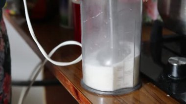 Mutfağa. Şeker bir kabın içine dökülür. Şekeri toz haline getirmek için yiyecek işlemcisi kullan..
