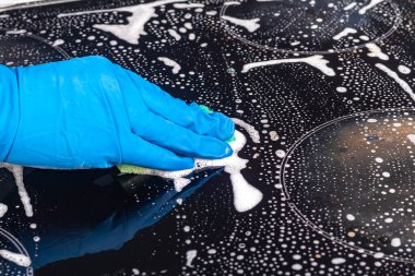 Mavi eldivenli kız elektrikli sobayı yıkıyor. Özel bir çözüm uygular. Yakın plan.