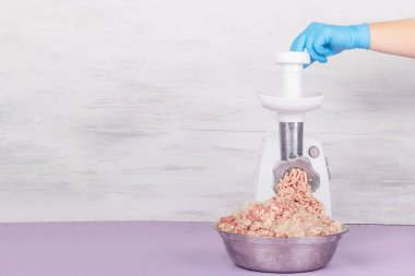 Elektrikli beyaz et öğütücüsü. Kıyma yaralıdır ve metal bir kasenin içinde yatar. Uzayı kopyala Metin.