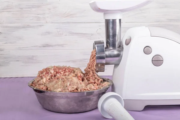 electric white meat grinder. Minced meat is wound and lies in a metal bowl. Copy space. Text.
