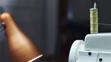 Dikiş makinesi üzerinde çalışan kadın. Pan vurdu. Mavi tonu.