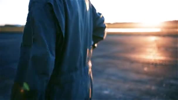 戦闘機パイロットは飛行場で日の出に対して歩く — ストック動画